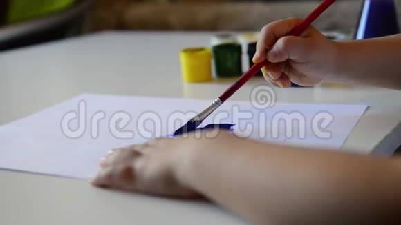 小男孩的手在纸上画画可爱的孩子坐着画画呆在家里视频的预览图