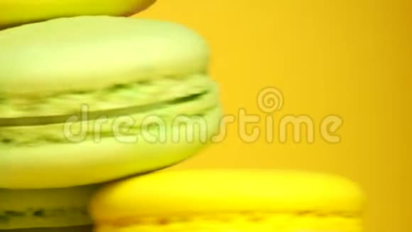 五颜六色的美味杏仁饼在黄色的背景上旋转视频的预览图