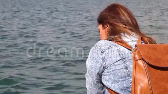 坐在海边的年轻女子棕色背包视频的预览图