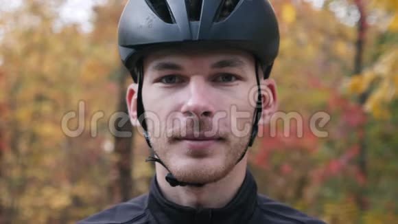 秋天美丽森林中年轻职业自行车手的肖像戴着运动眼镜的男性脸部特写镜头视频的预览图