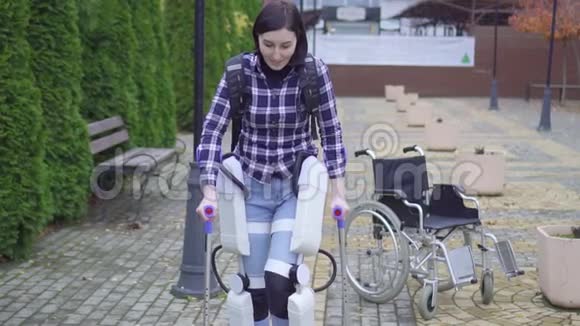 美丽的年轻瘫痪的残疾妇女正在学习在外骨骼的帮助下再次行走视频的预览图