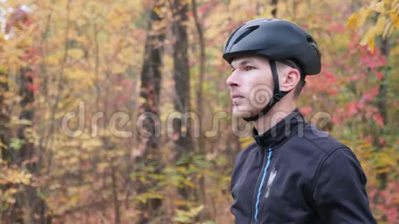 职业男性骑自行车的黑色运动服装和头盔准备在秋季公园训练和戴上眼镜骑自行车视频的预览图