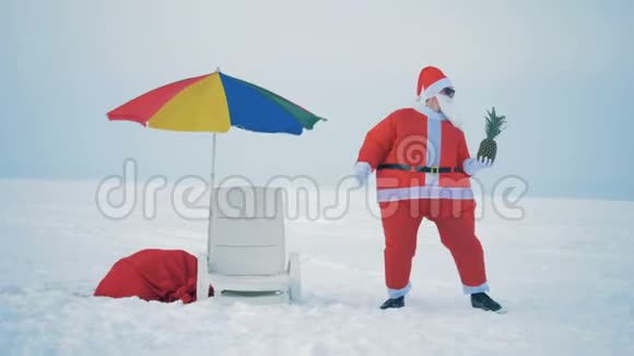 快乐的圣诞老人正和一个菠萝在甲板椅旁边跳舞视频的预览图