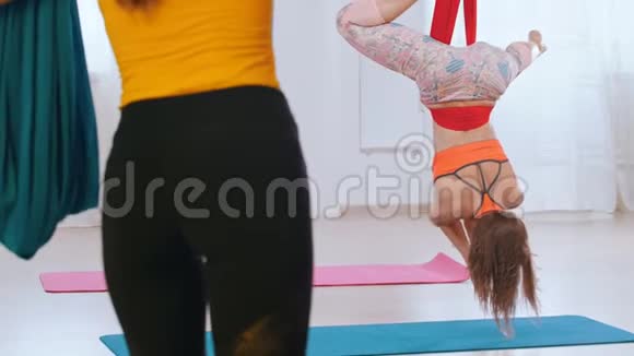 在教练的监督下一名运动女子倒吊在吊床上做瑜伽视频的预览图