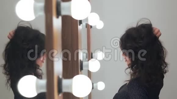 时尚的女性模特美丽的专业发型摆在镜子前灯泡在镜子里视频的预览图