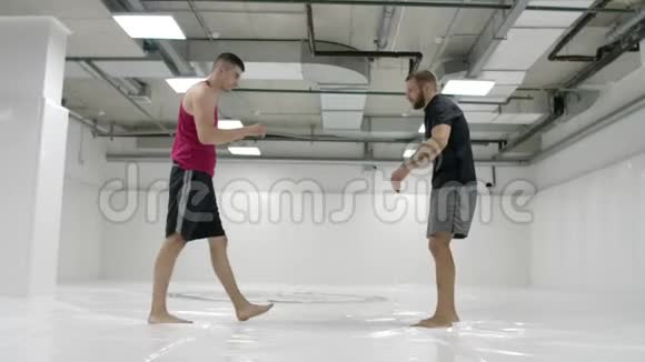 MMA战斗机练习摔跤技术白色大厅和榻榻米上的摔跤手一个穿红色T恤的男人和一个穿视频的预览图