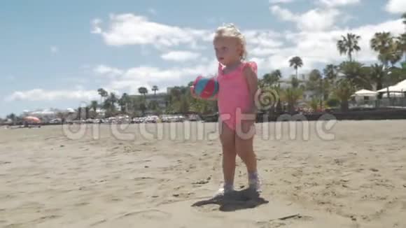 穿着粉红色泳衣在海滩上散步的可爱女婴视频的预览图