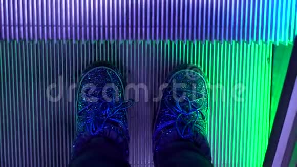 乘坐带有LED彩灯的自动扶梯可俯瞰穿月靴的女性双腿视频的预览图
