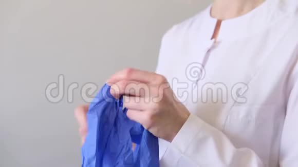 一位身穿白色制服的女医生戴上蓝色手套卫生治疗医药概念视频的预览图