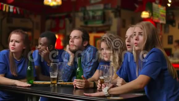 在啤酒酒吧穿蓝色t恤的情感粉丝多族裔的非裔美国人感到沮丧和悲伤因为视频的预览图