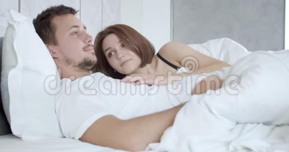 可爱的年轻夫妇躺在床上女人躺在男人的胸膛上4K视频的预览图