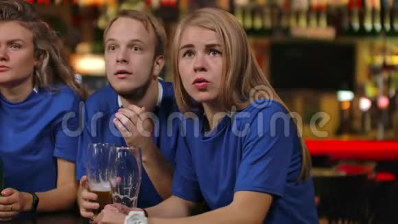 一群球迷情绪激动地在电视上的一家酒吧里观看体育节目他们穿着啤酒男女穿着蓝色T恤视频的预览图