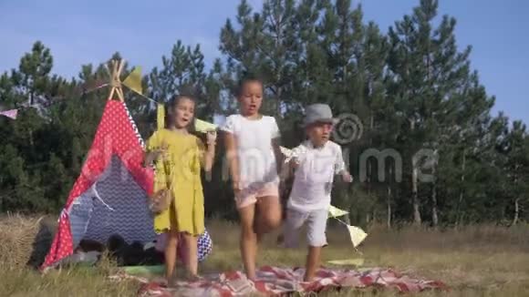 快乐的童年美丽的小女孩和有趣的男孩在森林里的空地上跳舞玩得开心视频的预览图