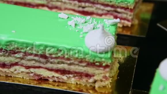 在黑色托盘上提供绿色釉层蛋糕部分的特写全景视频的预览图