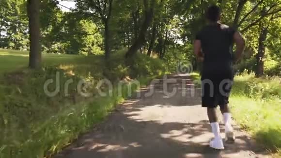 年轻的肌肉运动员在绿树丛中奔跑视频的预览图