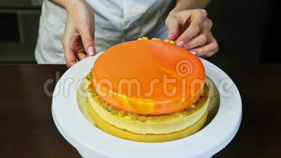 糖果师用黄色的小马卡龙装饰橙色的圆形奶酪蛋糕视频的预览图