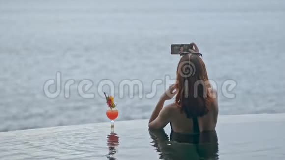 年轻女性模特使用智能手机自拍在巴厘岛度假村游泳池视频的预览图