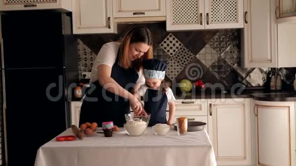 母亲和女儿穿着围裙在厨房里准备饼干面团肖像视频的预览图