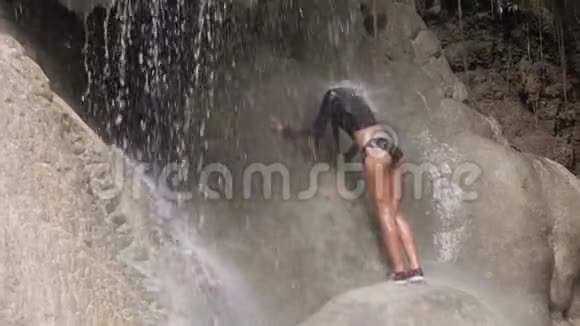 年轻女子在瀑布下放松喜欢洗澡假期概念视频的预览图