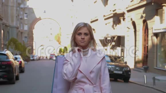 拿着纸袋的女士站在大街上站在汽车和建筑物的背景下视频的预览图