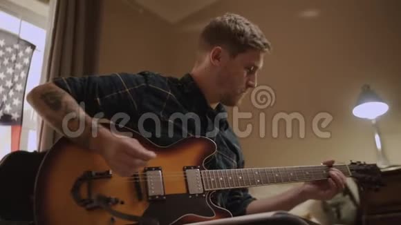 年轻的音乐家坐在他的公寓里用铅笔在音乐书上写笔记用吉他作曲视频的预览图