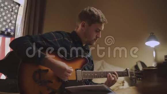 穿着便装的年轻人坐在床上深夜弹弦琴吉他视频的预览图