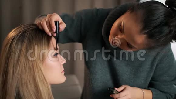 女造型师化妆师为女孩制作眉形造型面部特写年轻女子时装模特美容店视频的预览图