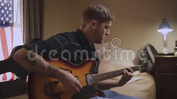 一位有经验的艺术青年在激情之后坐在床上弹吉他的特写镜头视频的预览图