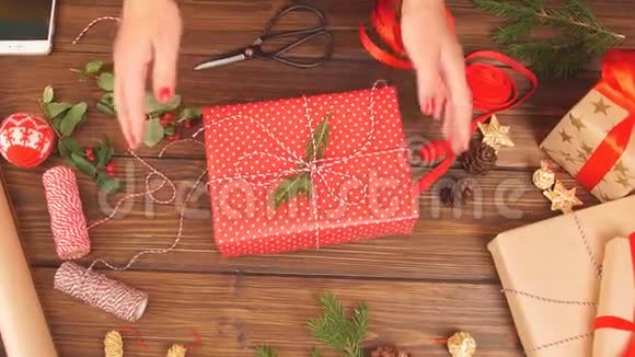 女人手把圣诞假日手工礼物绑在手工纸上用缠绕丝带视频的预览图
