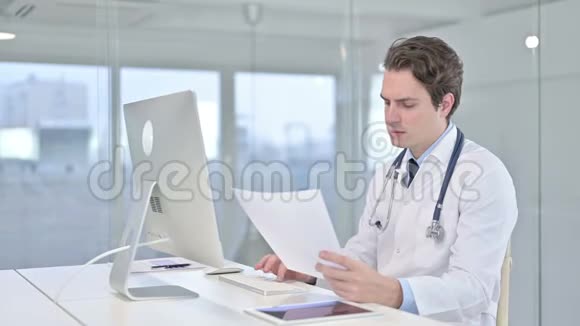 严肃的年轻医生在办公室的桌面上做文书工作视频的预览图
