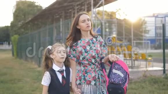 妈妈正带着小女孩穿着校服上学母女俩一起牵手上学视频的预览图