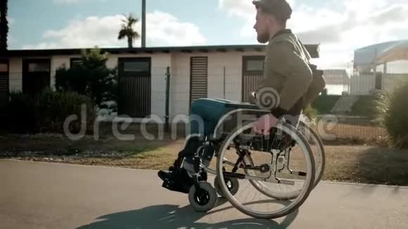 坐轮椅的腿瘫痪的年轻人独自走在城市的街道上视频的预览图