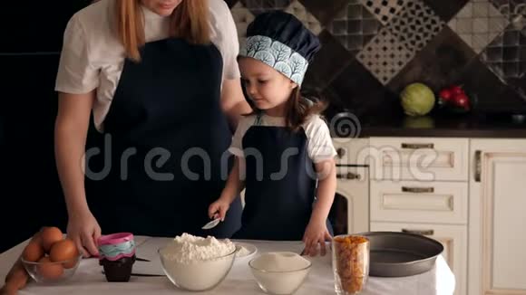 母亲和女儿穿着围裙在厨房里准备饼干面团肖像视频的预览图
