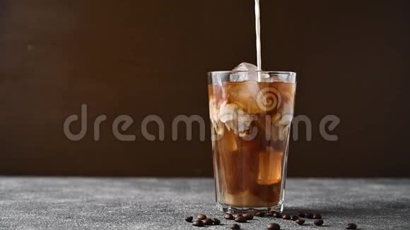 慢动作奶油倒入装有咖啡和冰的玻璃杯中视频的预览图