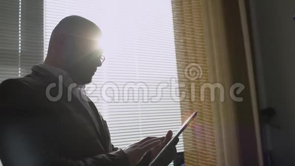 商人在办公室窗户附近做数字平板电脑使用数字平板电脑的人视频的预览图
