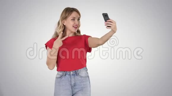 欢乐的女人30岁穿着红色t恤在散步梯度背景下自拍视频的预览图