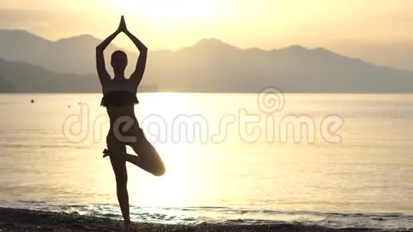 一个优雅的女孩在日出时在海滨做瑜伽姿势动作缓慢视频的预览图