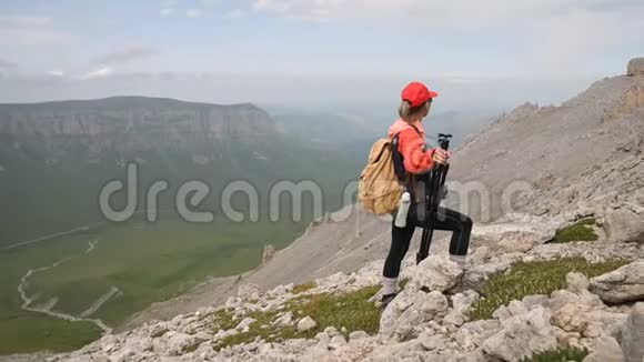 一位年轻的摄影师站在山腰上站在高原悬崖峭壁的背景下视频的预览图