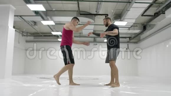 两名摔跤手动作缓慢希腊罗马摔跤手穿着T恤衫和外套在大厅里训练视频的预览图
