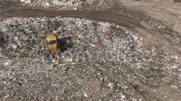 城市垃圾场推土机沿着填埋场移动铲平垃圾以食物垃圾为食的海鸥飞过它空中飞行视频的预览图