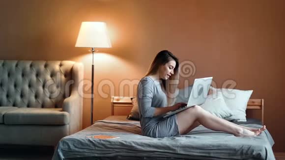 快乐的年轻女孩用笔记本电脑聊天放松舒适的卧室积极的情绪视频的预览图