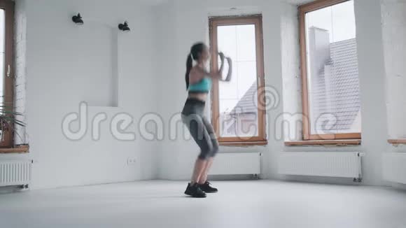 穿着运动服装的漂亮年轻健康的运动女孩在家做木板视频的预览图