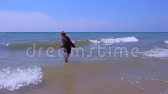 在风和日丽的假期里小男孩在海浪中玩耍和跳跃视频的预览图