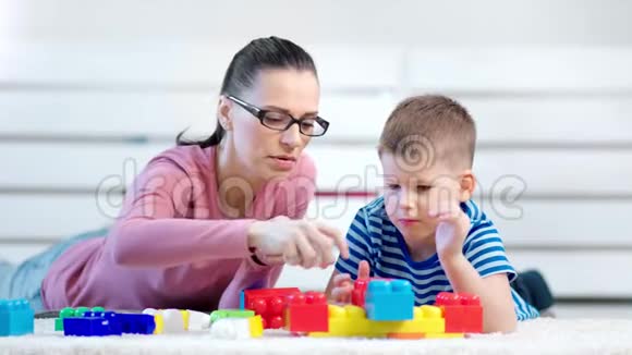 中等特写无忧无虑年轻的妈妈和小可爱的儿子玩建造师立方体视频的预览图