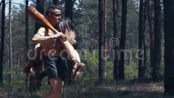 野蛮人扛着一个昏迷的女人在他的肩膀上穿过森林视频的预览图