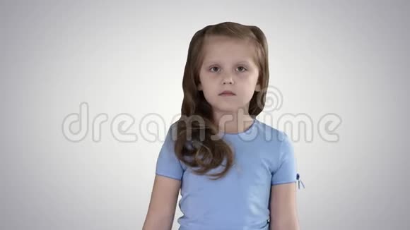 穿牛仔裤和蓝色t恤的小女孩走在渐变的背景上视频的预览图