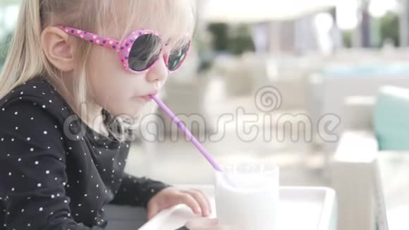 时髦的金发小女孩在夏天的咖啡馆里喝奶昔视频的预览图