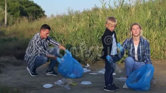 青年志愿者和孩子们在河岸的公园里收集垃圾视频的预览图