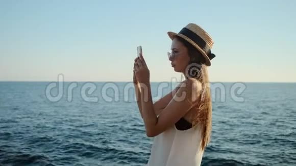 夏天女人正在用智能手机拍摄海景照片视频的预览图
