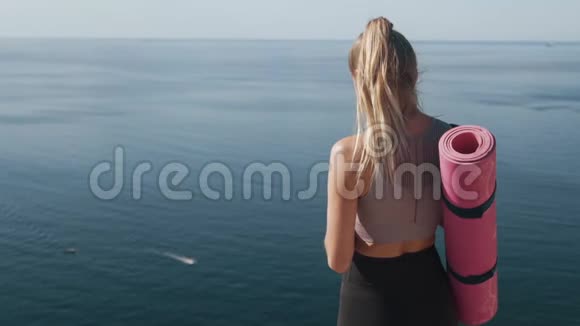 从背面看运动员女孩手里拿着手机背景是海洋视频的预览图